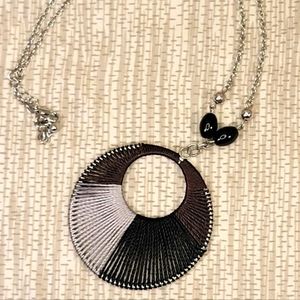 Round woven black and gray pendent on a silver necklace.